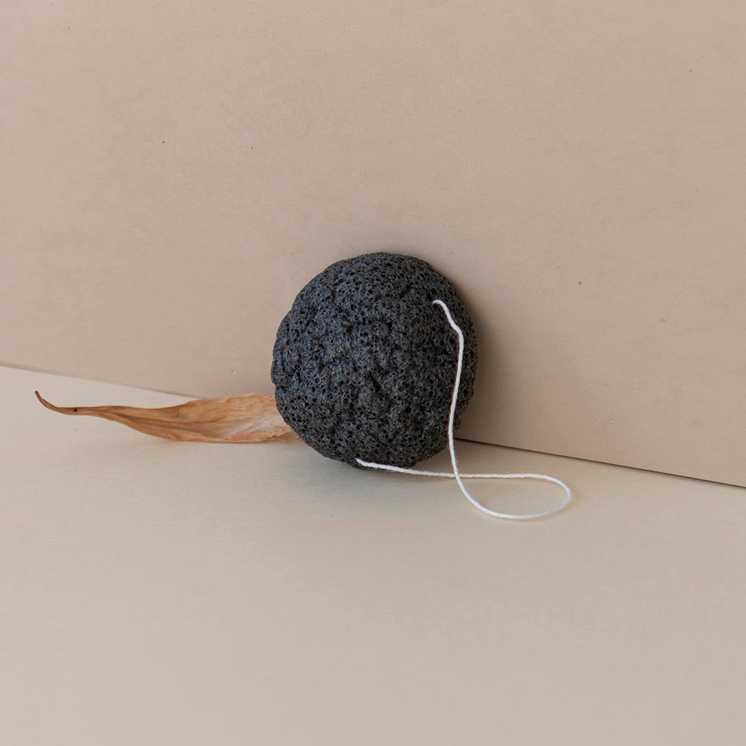 Esponja konjac apoyada sobre pared donde se muestra hilo blanco para colgar después de su uso