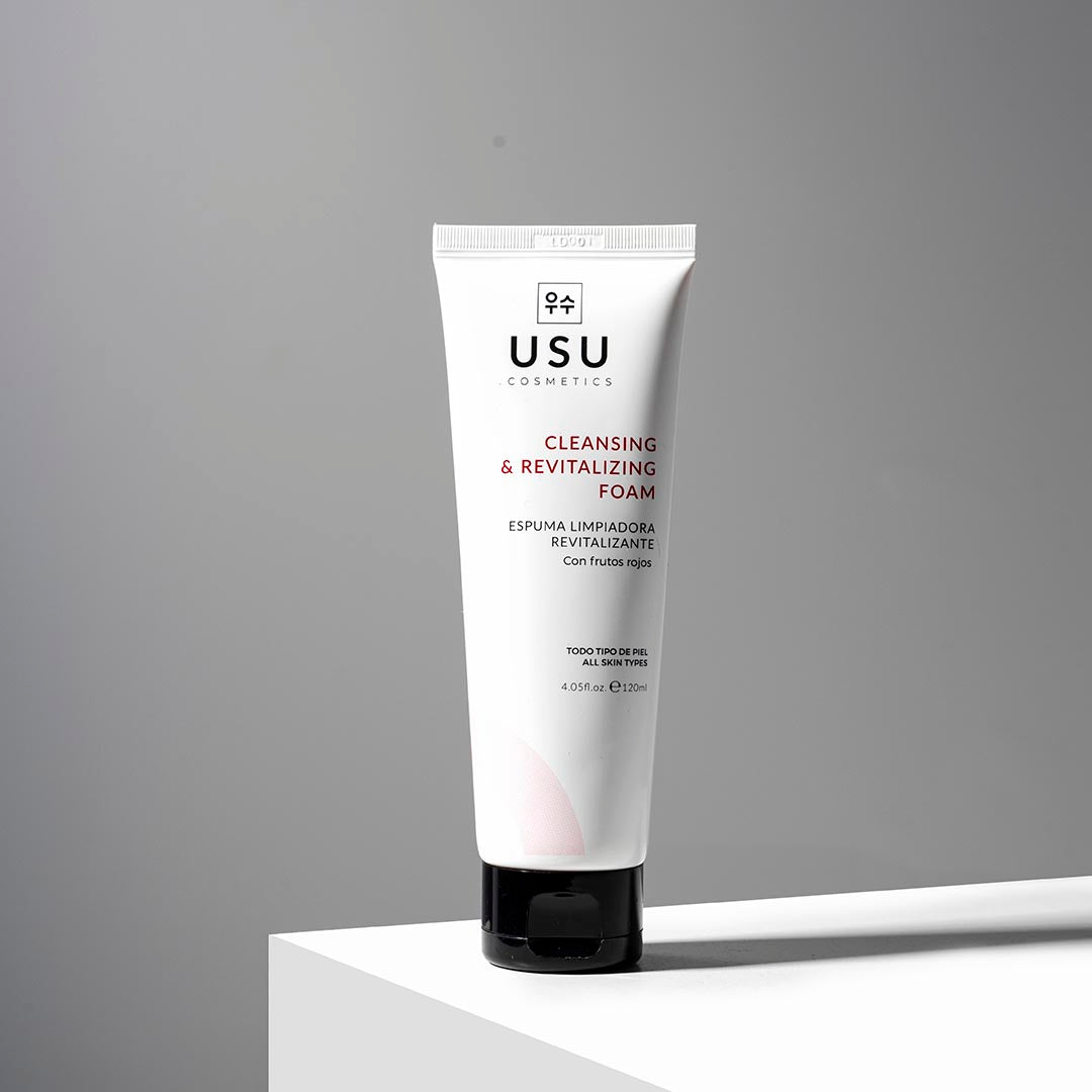 Envase de la espuma limpiadora revitalizante sobre superficie blanca