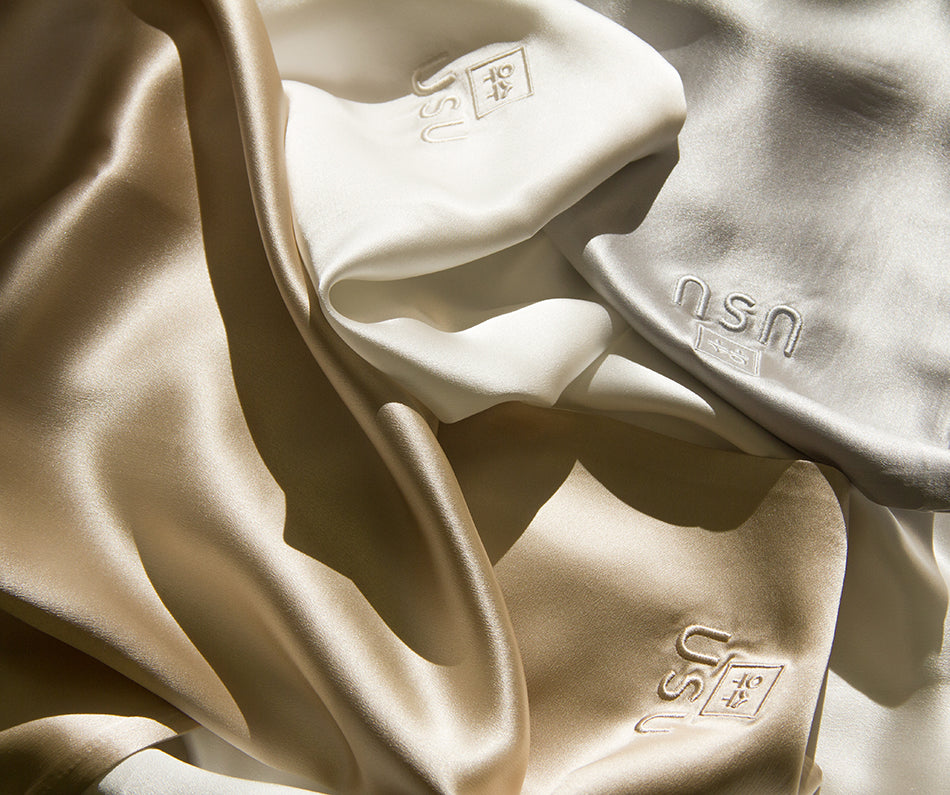 fundas_de_almohada_blanca_gris_y_champagne_sobre_cama de seda natural 22 Momme, ideal para un descanso reparador y un ritual de belleza coreano.