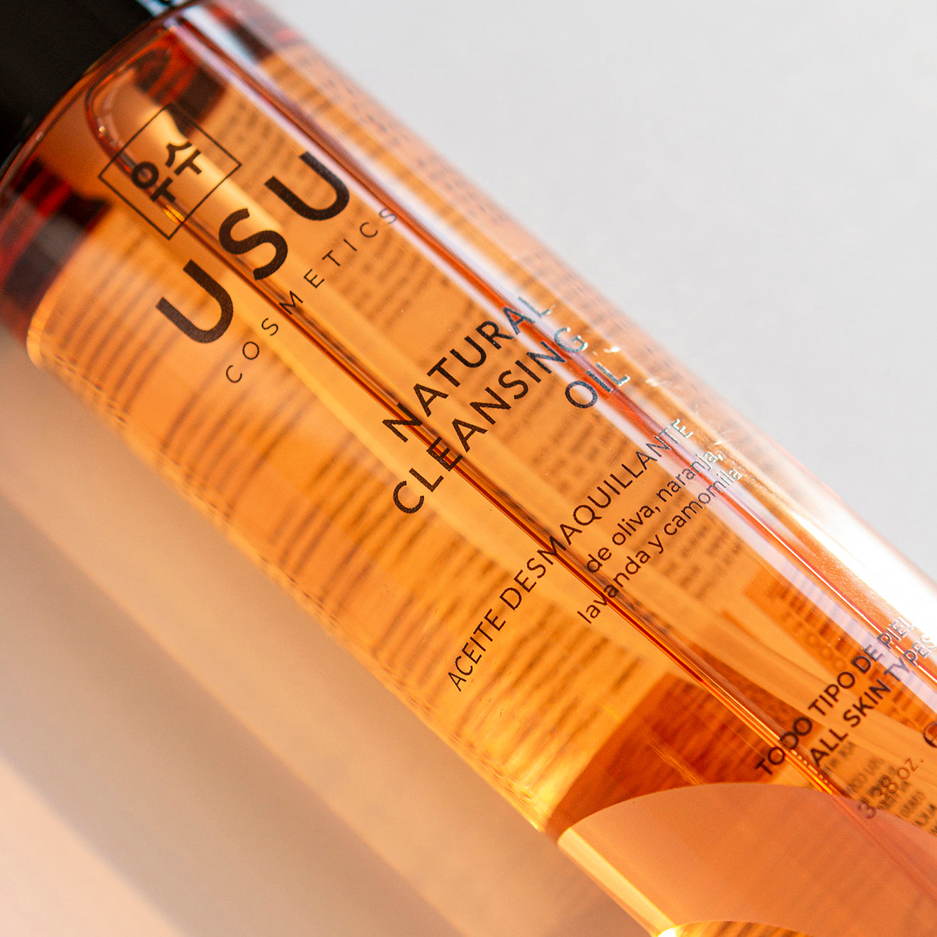 Primer plano de bote de aceite desmaquillante de USU Cosmetics con aceites esenciales 